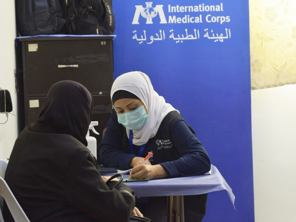 A health educator registers a patient and assists with data entry during peak hours.