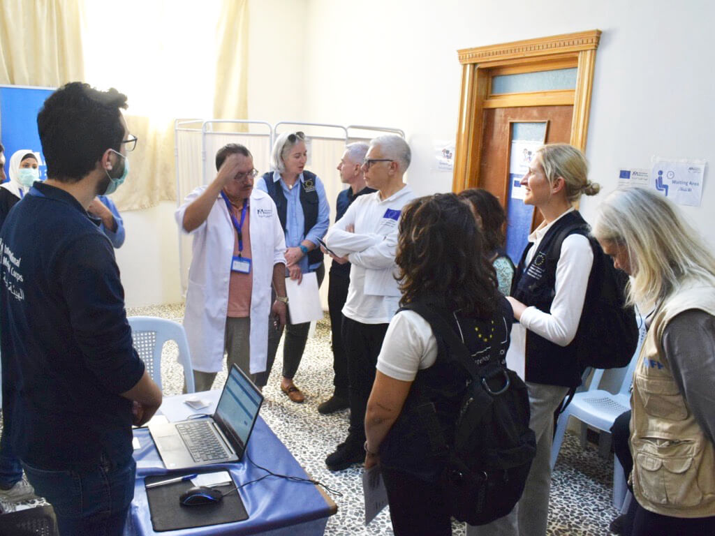 International Medical Corps staff talk to EU officials about the different healthcare services we provide at the Misraba MMT with the EU’s support.
