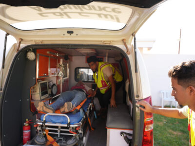 Trainees load a “patient” into an ambulance.