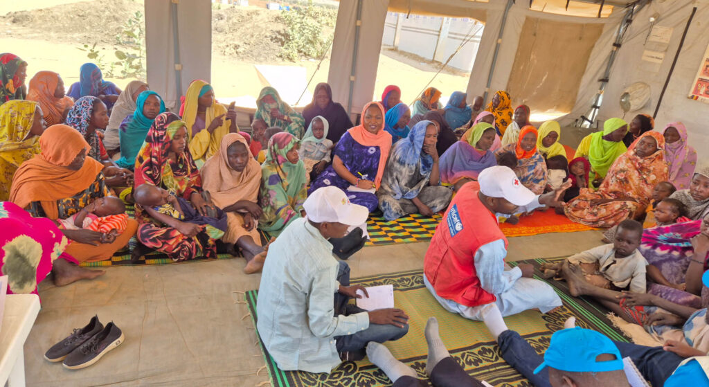 Martha Nakakande (front row, in blue dress and orange headscarf) visits a breastfeeding tent in Adre camp in Chad as part of our IYCFE support to UNICEF Chad.