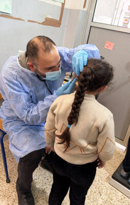 A physician from the Mashael PSU examines a young girl at the Haush Harimeh High School.