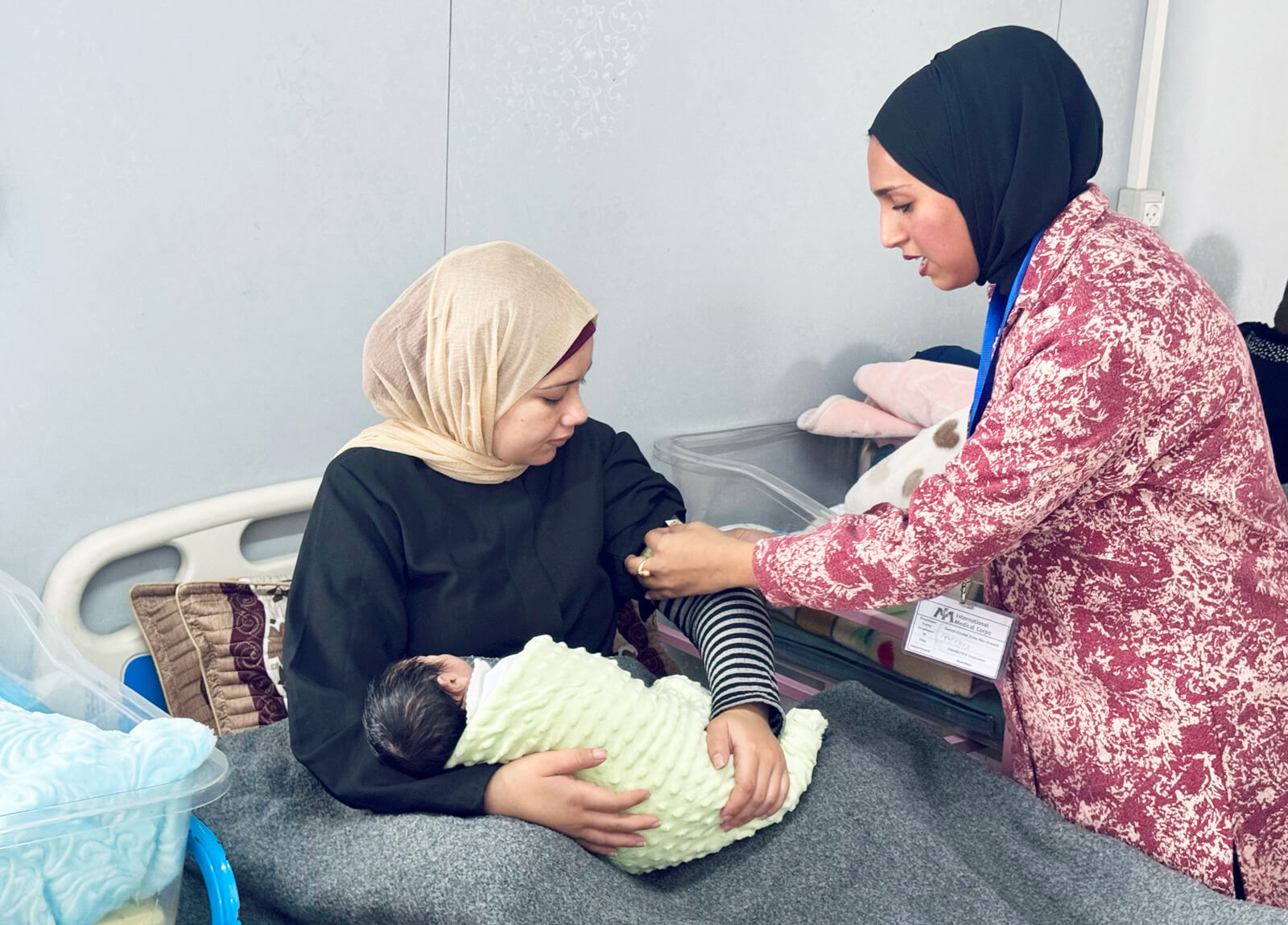 An International Medical Corps nutritionist (right) follows up with a mother after delivery at the maternity ward of the Deir Al Balah field hospital.