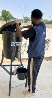 A staff member adds chlorine to a handwashing station at the main entrance of the general hospital in Damboa.