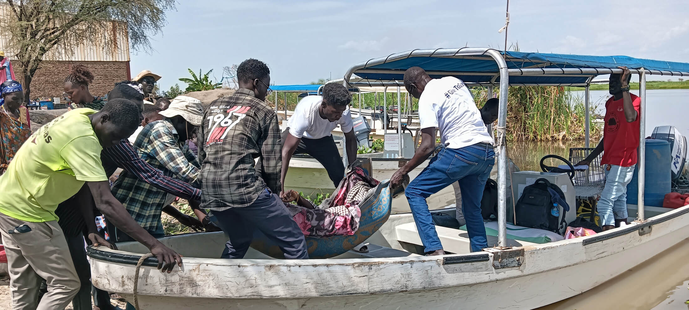 Nyabol Ochol is carried by International Medical Corps staff and community members to the speedboat that carried her from Kodok to Malakal.