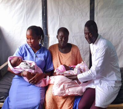 Senior Midwife Supervisor Chuol Ker Yat Pan sits beside Nyajuok Gai, who safely delivered twins in Juba IDP Camp.