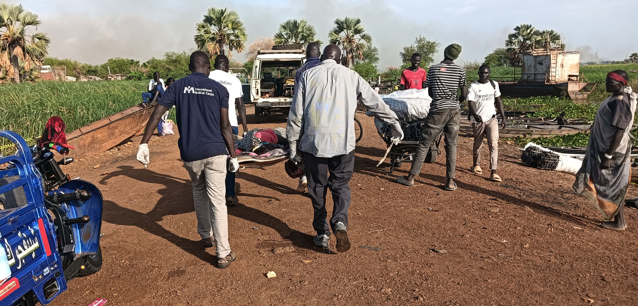 International Medical Corps staff and community members carry Nyabol on a stretcher from the dock in Malakal to the ambulance that took her to Malakal Teaching Hospital.
