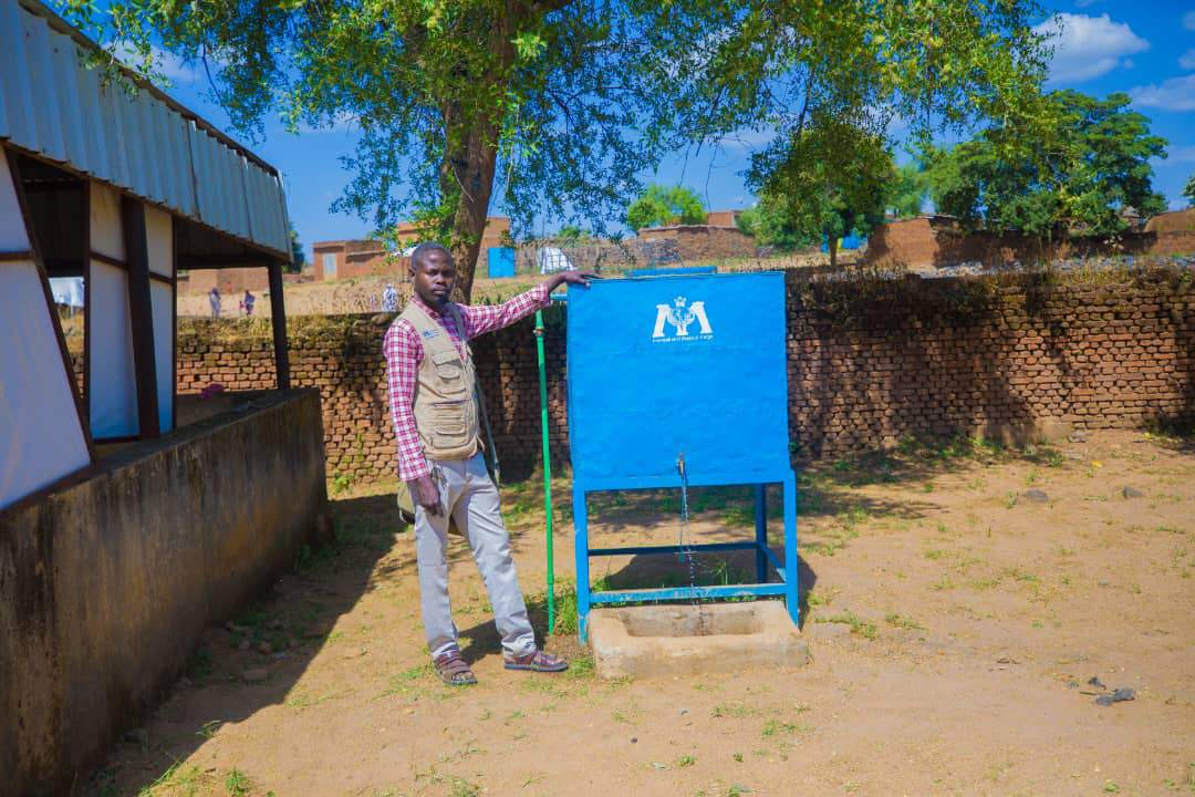 A member of the International Medical Corps WASH team in Sudan stands beside a recently installed water tank at Golo Hospital.