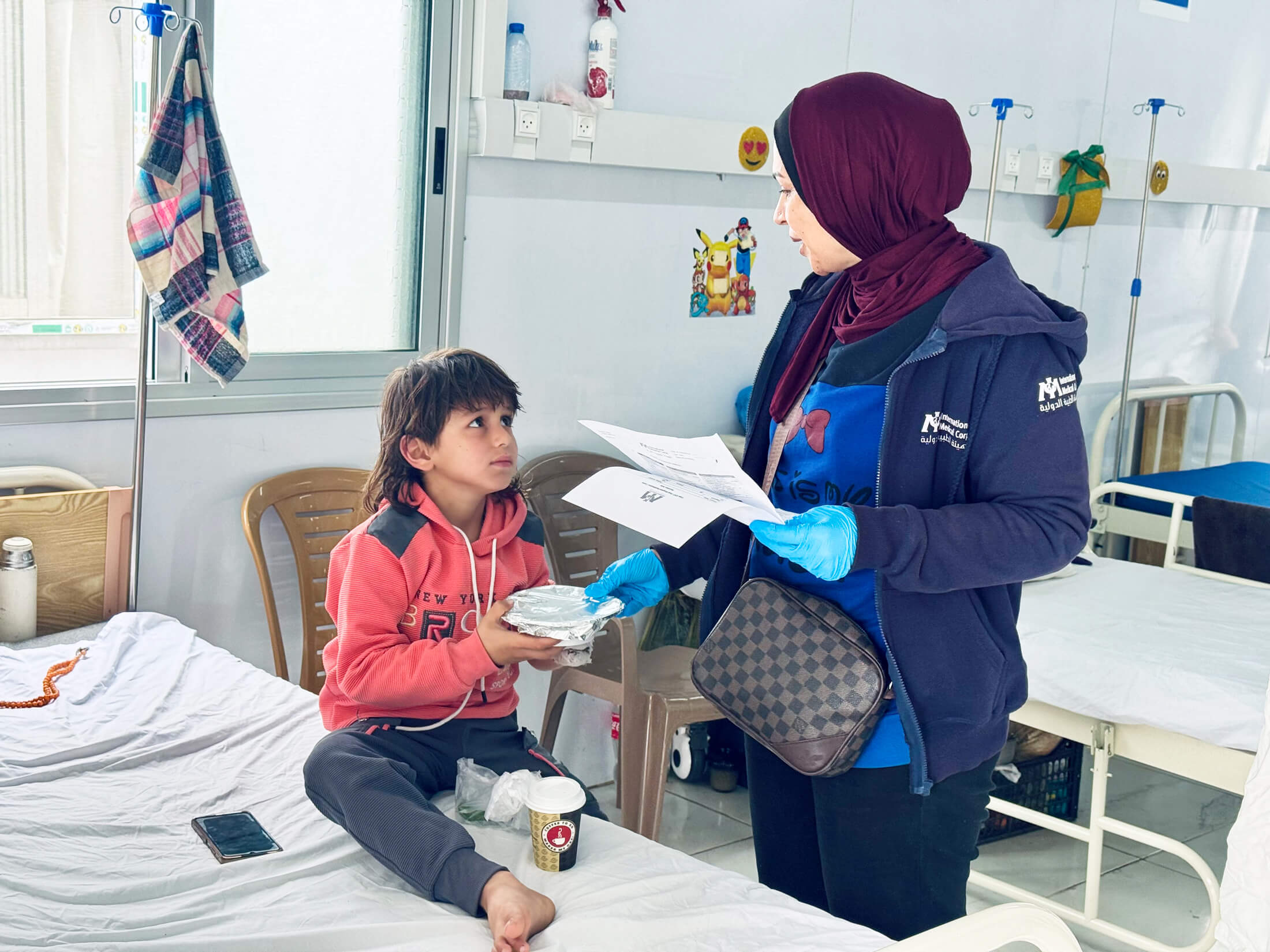 Chef Rasha hands a special meal to a child admitted in the inpatient department of the Gaza City field hospital.