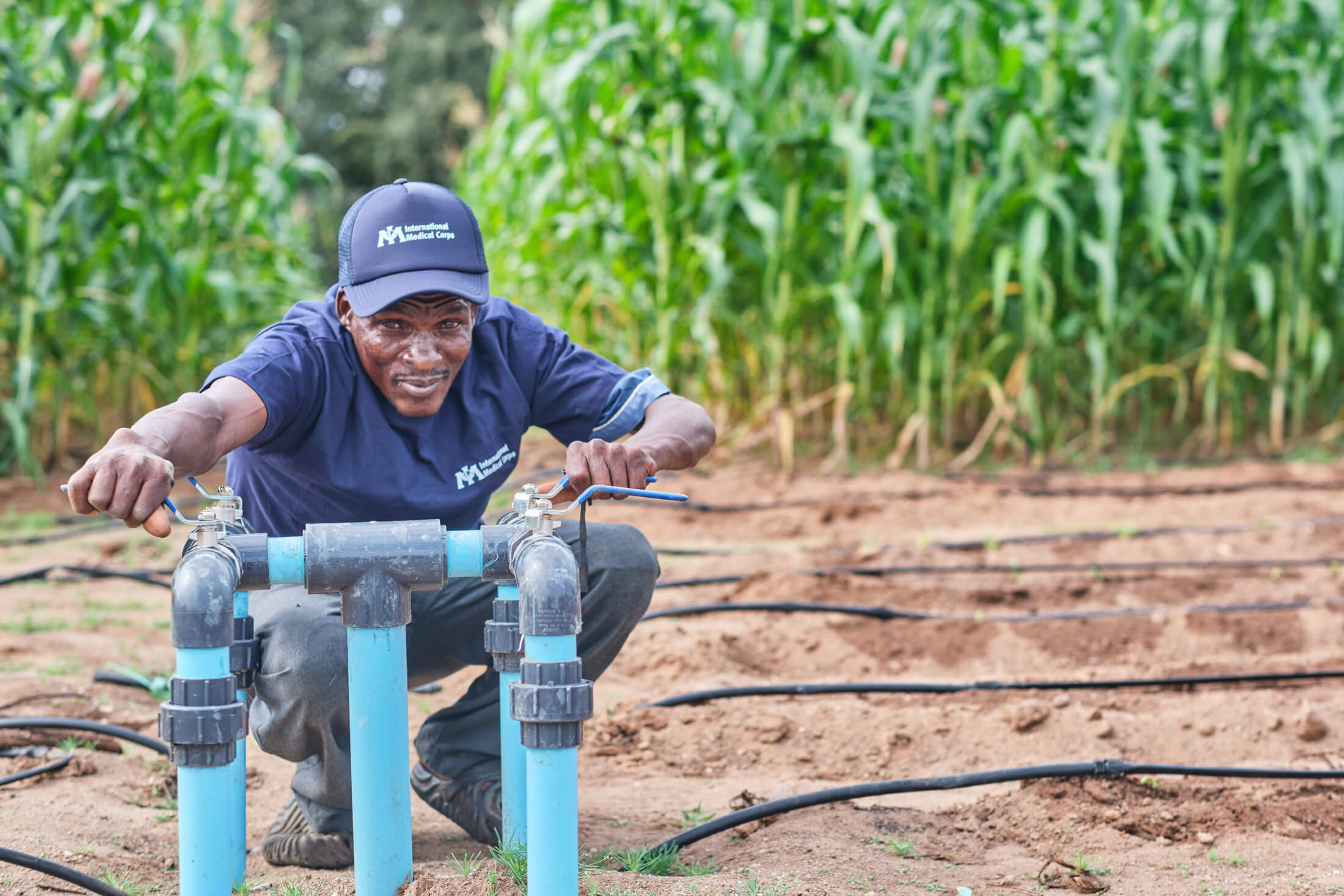 A staff member demonstrates how to control the drip irrigation system in a communal plot in Novhe village, where International Medical Corps worked with a local partner to provided a solarised borehole installation and communal nutrition garden.