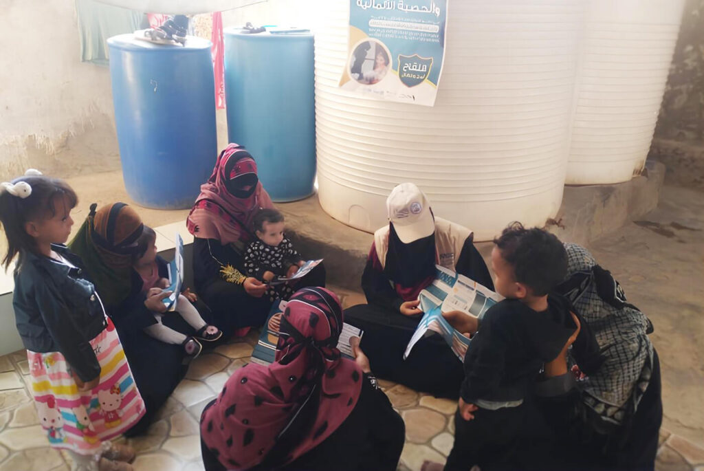 A CHV (wearing a cap) educates a group of mothers in Lahj governorate about the importance of vaccinating their children.