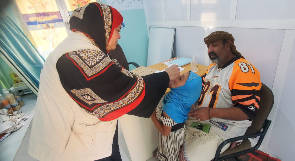 Three-year-old Rayhan receives her first vaccine dose as her father looks on.